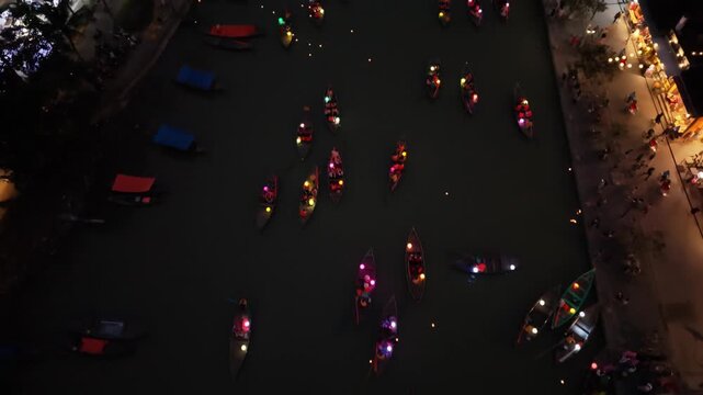 Colorful lanterns light up boats on the river in Hoi An, Vietnam, with people enjoying the vibrant atmosphere along the waterfront at night