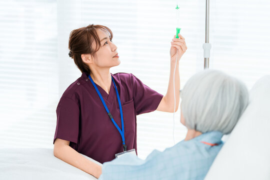 Female Nurse Supporting a Senior Woman Receiving IV Treatment in a Hospital