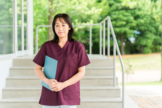 Female Medical Staff in Scrubs Holding a Patient Chart While Working at a Hospital