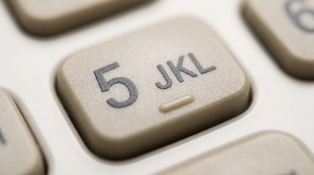 Macro photograph of a vintage beige telephone numeric keypad button displaying the number five and letters JKL