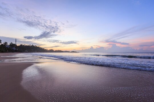 Tropical Beach Sunset Over Ocean Waves and Sandy Shore