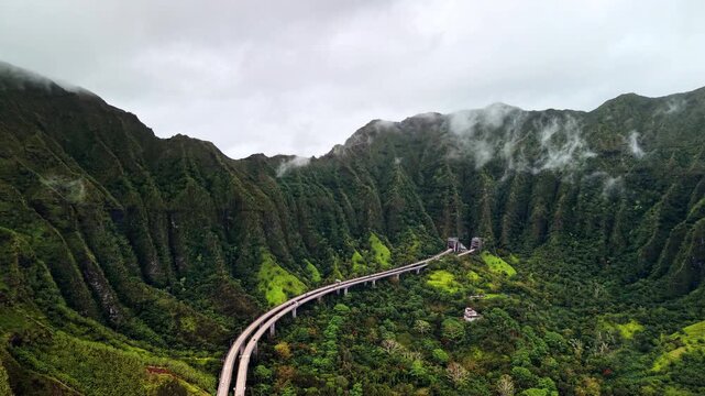 Aerial drone view of the highway viaduct running below the sharp fluted ridges of the Koolau mountains, Oahu, United States