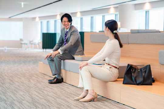 職場の共用スペースで会話が盛り上がるビジネスパーソン
