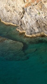 Vertical video of coastal rocks and water near Karavostasi beach on Bali mediterranean resort, Crete