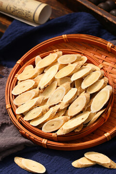 Dried slices of astragalus root in a wooden spoon and basket,traditional Chinese medicine