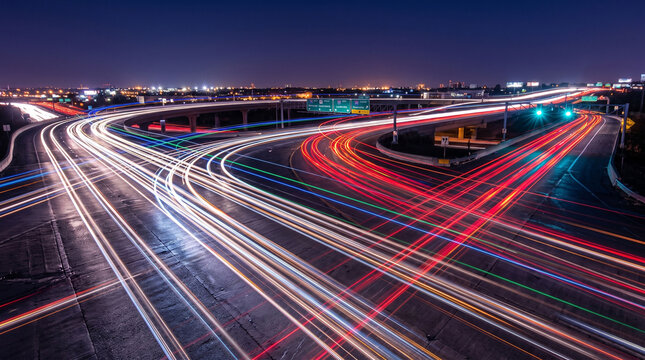 Long exposure light trails of traffic on a curved highway leading to the city skyline at night, Night traffic on a busy freeway with red and white blurred light streaks and cityscape.