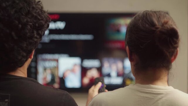 Couple deciding what to watch on streaming service using remote control at home