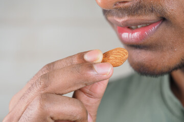 Person with almond near lips in kitchen
