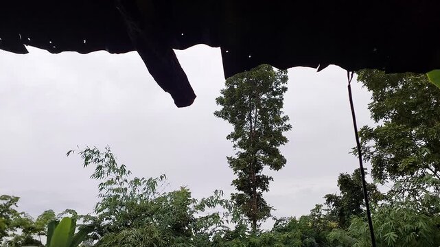 Rainwater dripping from a dark zinc roof edge against an overcast sky