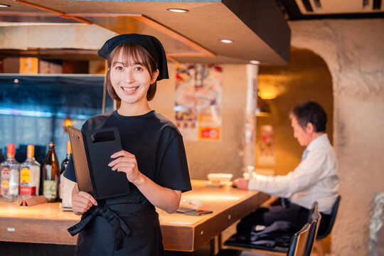 居酒屋で伝票を持つ若い女性スタッフ