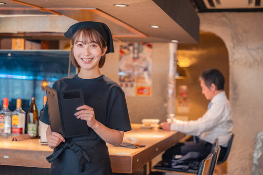 居酒屋で伝票を持つ若い女性スタッフ