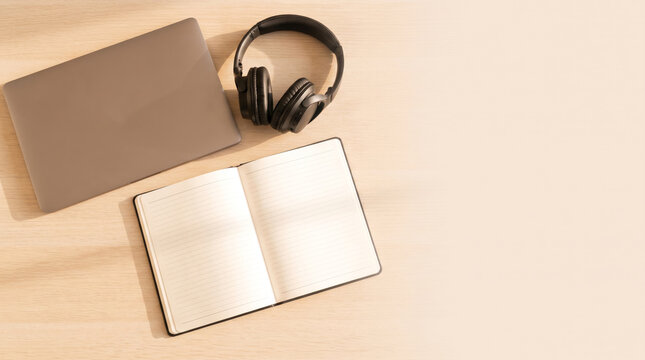 Overhead laptop and headphones on warm wooden desk