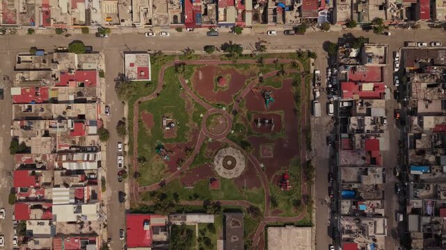 Top down drone descent over a residential neighborhood park in Ecatepec, Mexico, with houses and urban surroundings on a sunny day