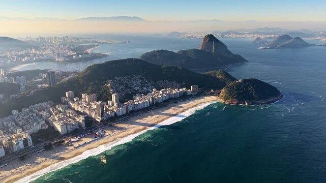 High-altitude aerial drone view of Copacabana beach, the green hill of Leme and Sugarloaf Mountain above the dense city, Rio de Janeiro, Brazil