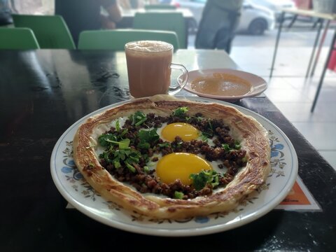 Traditional Malaysian roti sarang burung spesial flatbread with beef and sunny side up eggs