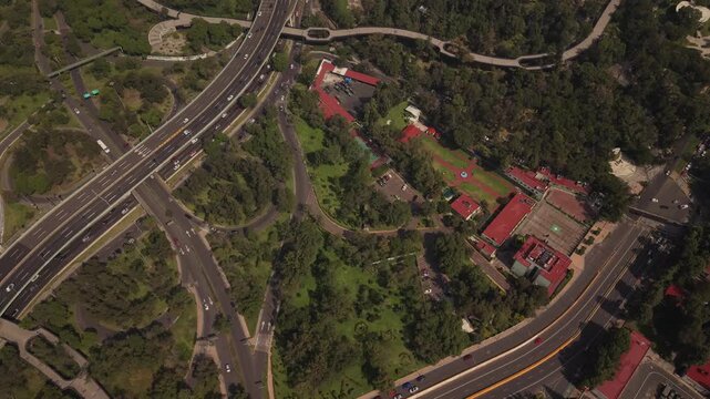 Static overhead drone view of busy highways and streets in Mexico City, with heavy traffic, vehicles, urban infrastructure, and surrounding vegetation.