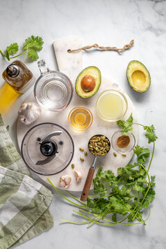 Above view of ingredients all around for making a avocado cilantro dressing. 