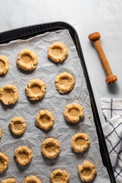 A parchment lined baking sheet topped with formed cookie cups ready for filling.