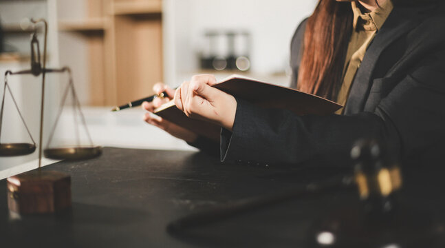 female lawyer in suit at workplace with laptop, gavel and femida in office