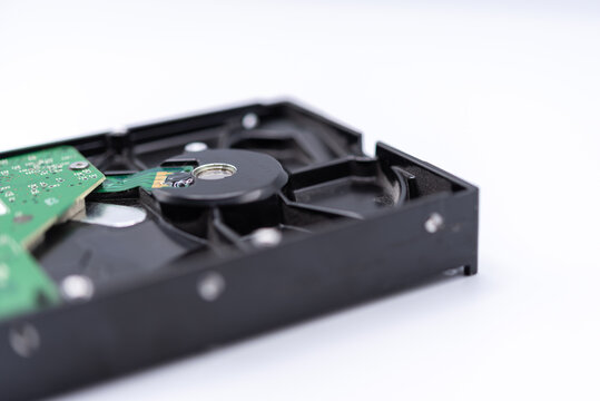 Close up of computer hard disk drive showing the circuit board spindle motor black metal casing isolated white background copy space for data storage technology
