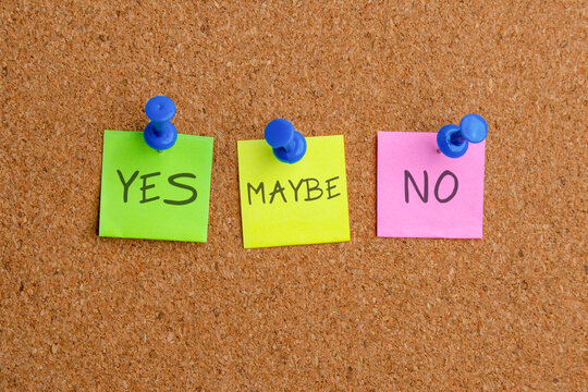 Three sticky notes with the words YES, MAYBE, and NO pinned to a corkboard. Decision making, survey options, voting, and choice concept.