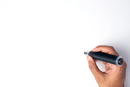 Hand holding a black marker pen to write against a blank white background. Copy space for text.