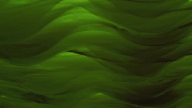 Abstract background of dark green silky fabric moving in smooth undulating waves. Elegant, mysterious, and luxurious textile texture footage ideal for backgrounds and visuals.