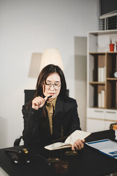 female lawyer in suit at workplace with laptop, gavel and femida in office