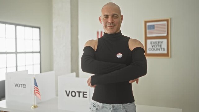 Middle aged bald man with bare shoulders and folded arms at a voting booth inside a civic building wearing an i voted sticker and smiling; pride duty.