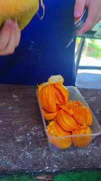 Bright orange-fleshed cempedak fruit is displayed in Penang, Malaysia, showing the edible segments and seeds of this tropical fruit variety - vertical shot