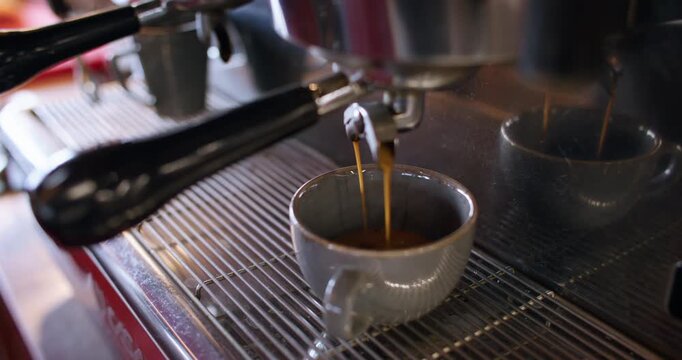 Coffee shop. Making hot drink. Aroma caffeine brown liquid streaming filling ceramic cup from metal horn restaurant cappuccino machine.