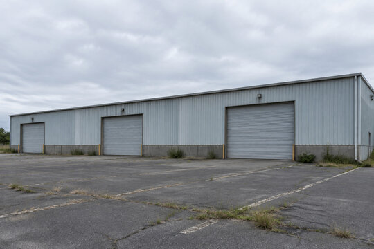 Closed industrial building with empty parking lot, unemployment and economic downturn concept