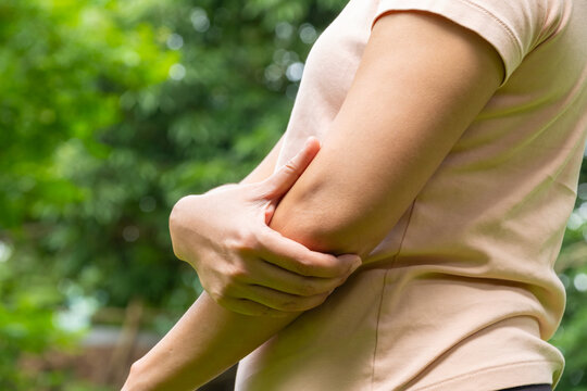 A woman has pain in his elbow and tendon muscles and he relieves the pain with a massage. Health and healing concept	