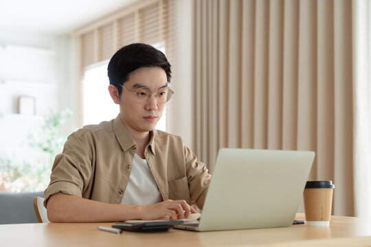 Young Asian man working on laptop at home