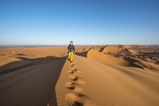Young man running on sand dune, Erg Chebbi, Merzouga, Sahara, Morocco