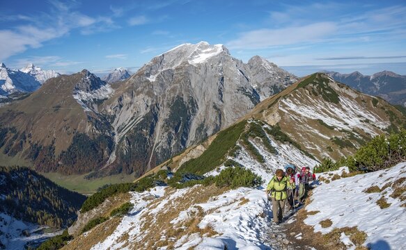 Three hikers on a hiking trail with snow in autumn, hike to the summit of the Hahnenkampl, behind Gamsjoch and Gramaijoch, Engtal, Karwendel, Tyrol, Austria