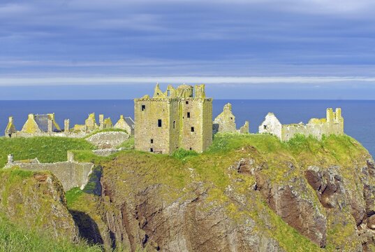 The ruins of a castle lie on a cliff in the evening sun, Dunnottar Castle, Stonehaven, Aberdeenshire, Scotland, United Kingdom