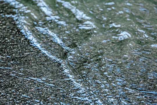 rainwater floods a city street. asphalt road after heavy rain. closeup view.