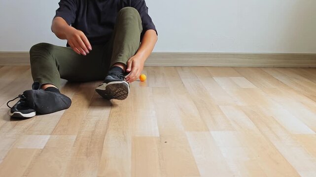 Person sitting on floor untying and taking off sneakers after an indoor workout session