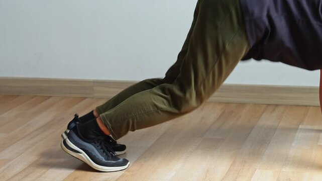 Close-up on legs and feet executing dynamic mountain climbers in pushup plank position