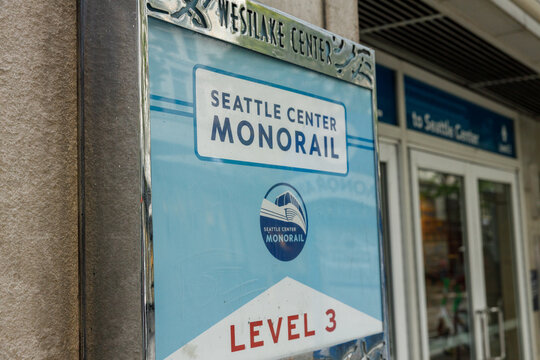 A framed Seattle Center Monorail Level 3 sign beneath a chrome Westlake Center header, its logo and arrow pointing riders down toward the station entrance doors.
