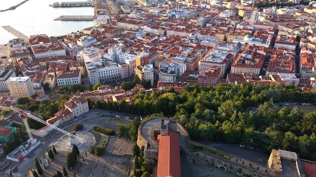 Aerial drone view of the castle esplanade on the hill with the old city and the port stretching to the sea below, Trieste, Italy