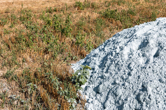 Pile of agricultural lime on a harvested stubble field ready for autumn spreading, used for soil liming, acidity correction, pH management and improving agricultural soil.