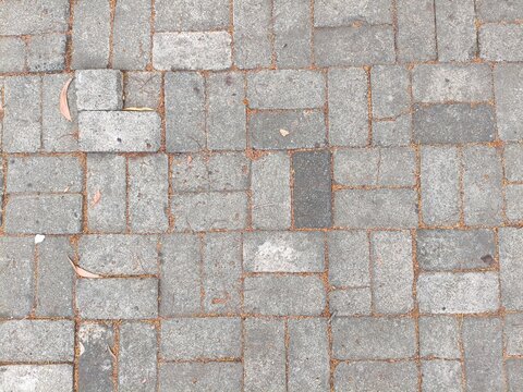 Overhead angled view of interlocking rectangular grey concrete cobblestone paving
