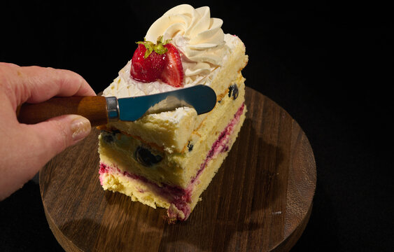 piece of fruit cake and a cutting knife in hand