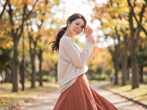 紅葉が美しい公園の散歩道で振り返り笑顔を見せる女性
