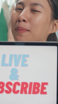 Vertical Screen : Young Asia lady beauty blogger wear crop top look at camera use digital tablet show screen online live talk follower introduce ask audience like subscribe share her chanel at studio.