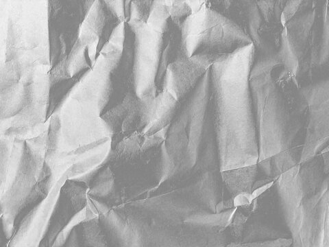 Crumpled silver metallic foil paper texture with wrinkled folds for luxury product background design.