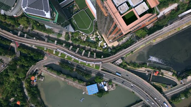Top-down aerial view of modern urban infrastructure in Jakarta, Indonesia. Roads, elevated railway tracks and buildings seen from directly above.