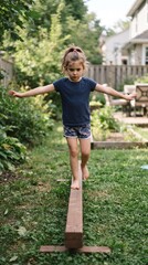 Fototapeta premium Young girl balancing on a wooden beam in a backyard garden
